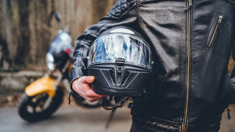 Rider holding motorcycle helmet under arm