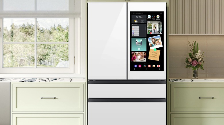 A white side-by-side Samsung refrigerator in a kitchen with a screen