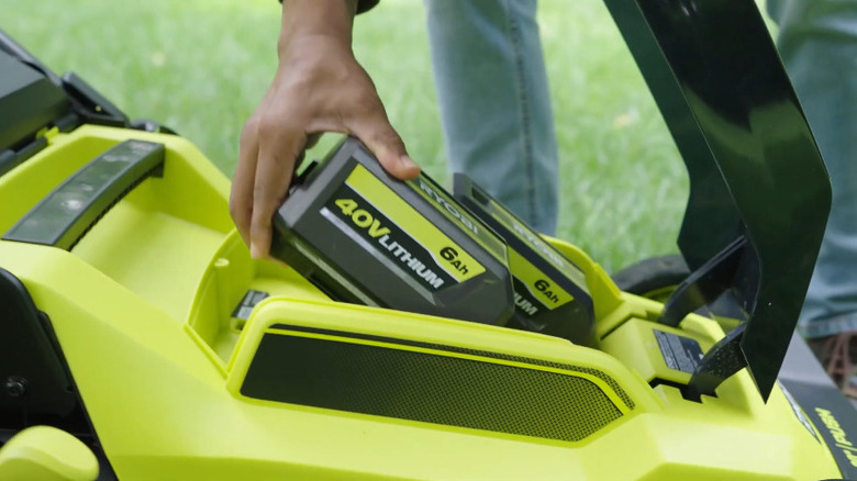 Hand putting in 40V 6Ah battery into Ryobi lawn mower