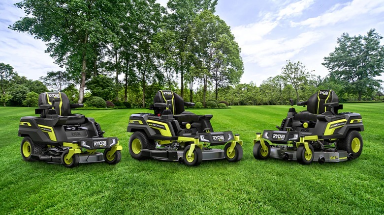 3 Ryobi lawn mowers over a grassy field
