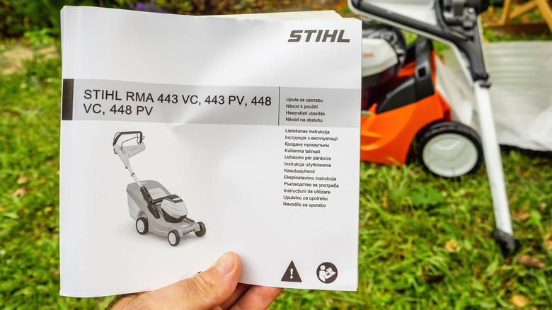 A person holding a Stihl RMA lawn mower instructions