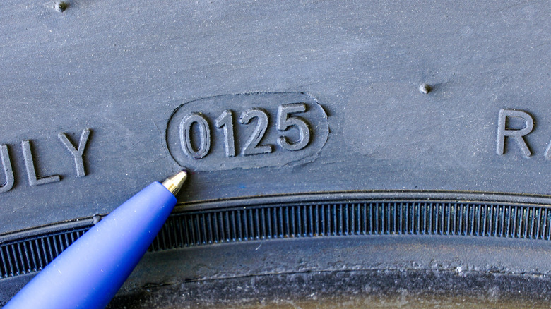 Tip of a pen pointing to the tire manufacturing date