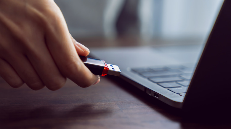 Person connecting flash drive to laptop