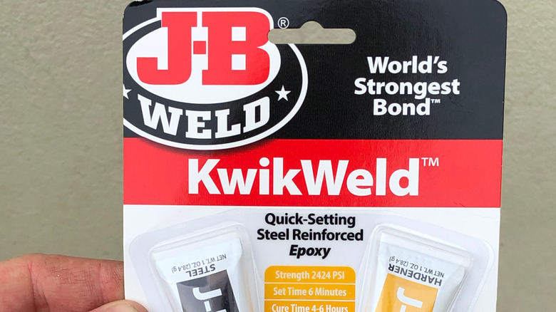 Close-up of J-B Weld KwikWeld packaging, held in a person's hand