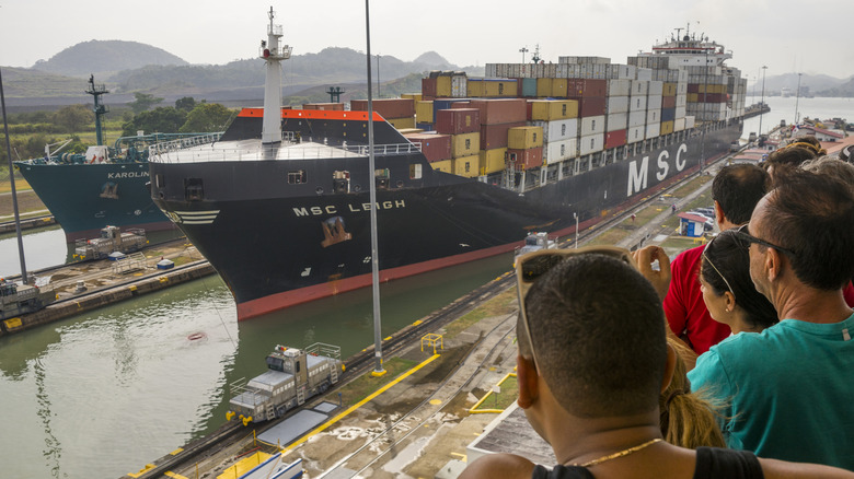 Tourists watch a container ship navigate the Panama Canal.