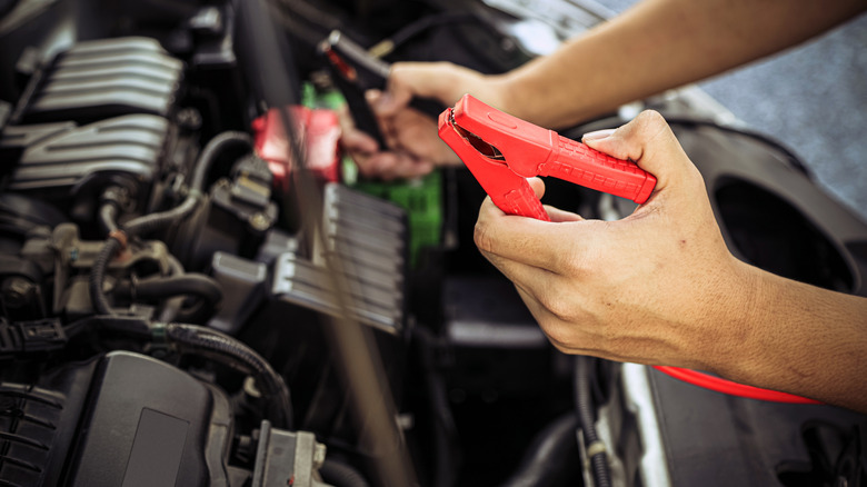 Car mechanic holding car booster cables for jump starting a car