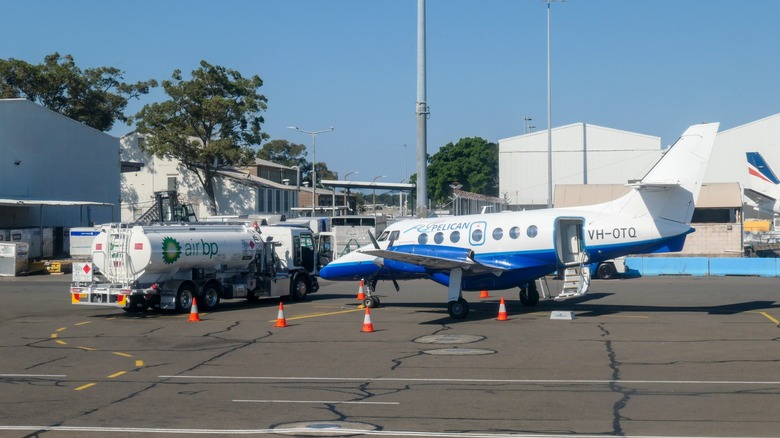A fuel truck pulling up beside a small plane