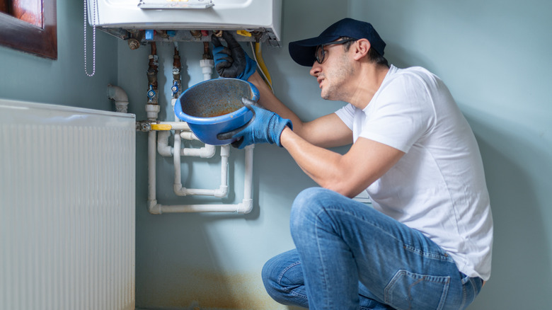 Professional inspecting a white gas water heater for issues