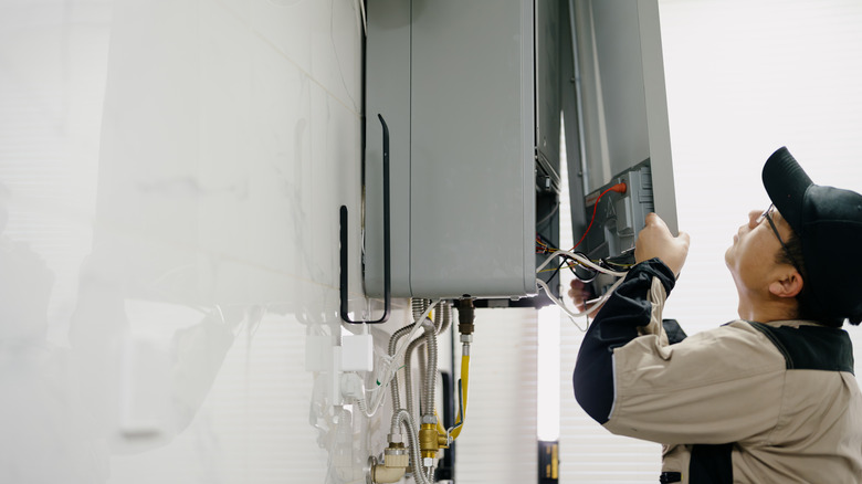 Professional taking apart the front panel of a gas water heater