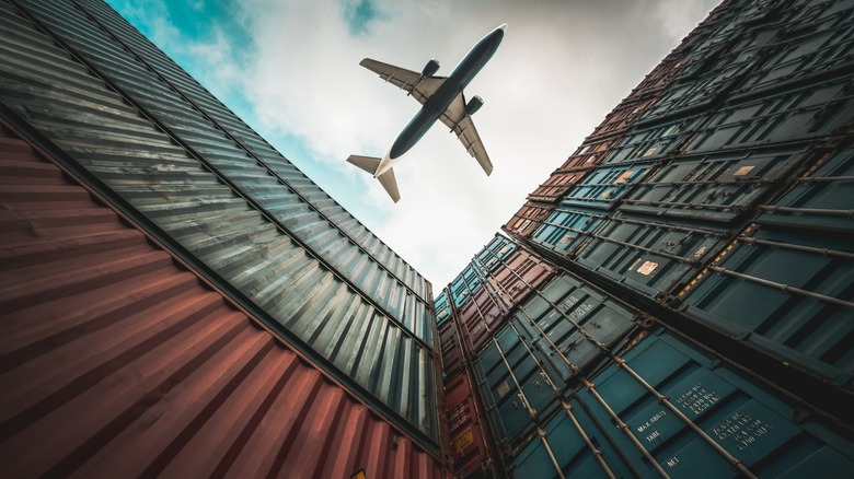 Freight airplane over shipping containers