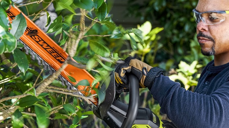 man using a Ryobi 18V ONE+ HP Brushless 24-inch Hedge Trimmer