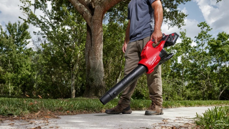 man holding red Milwaukee blower