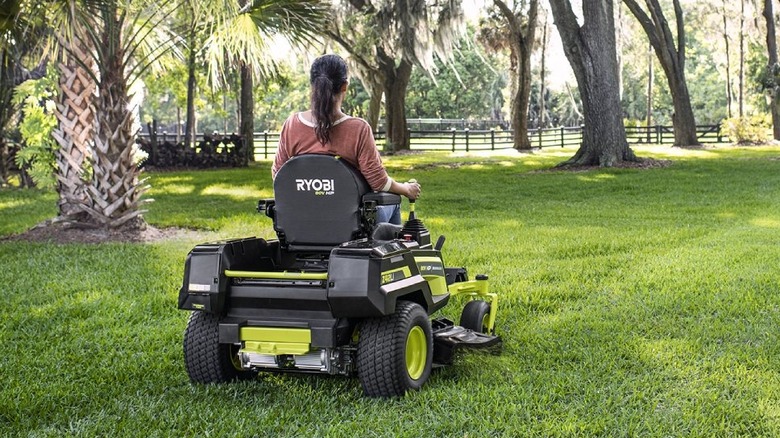 woman riding a zero turn on lawn