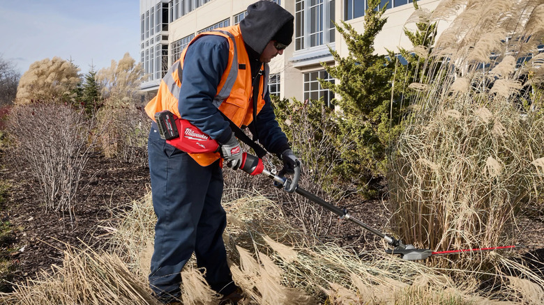 Worker uses a Milwaukee M18 Fuel Pole articulating hedge trimmer