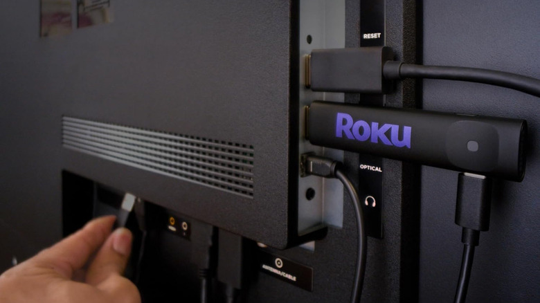 Roku streaming stick plugged into the back of a television