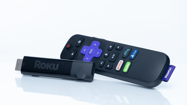 A close up of a Roku streaming stick 4K with remote control in a white background
