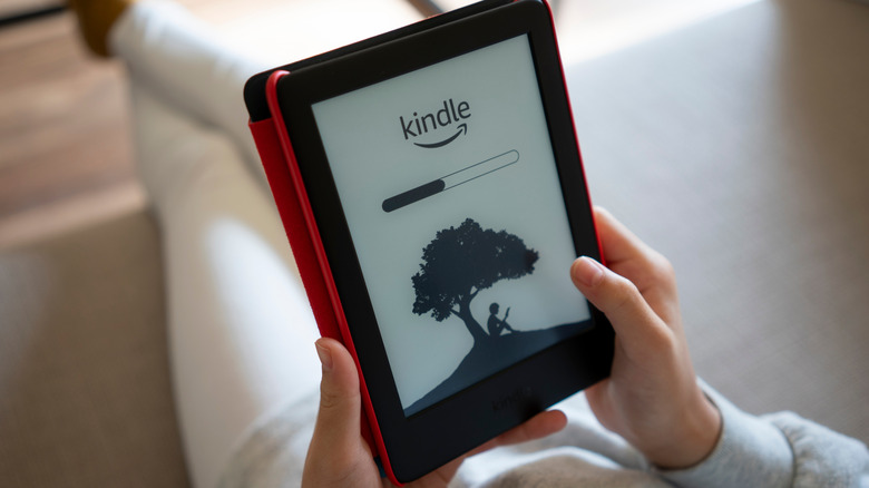Close-up of a woman holding an Amazon Kindle e-reader in a red case