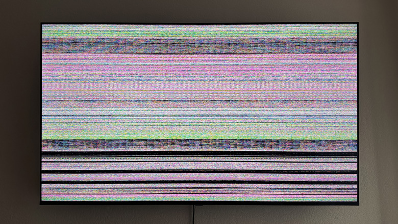 A modern TV mounted to the wall with blurry colored stripes displayed instead of a picture