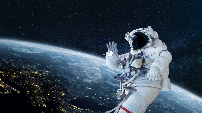 astronaut waving above Earth