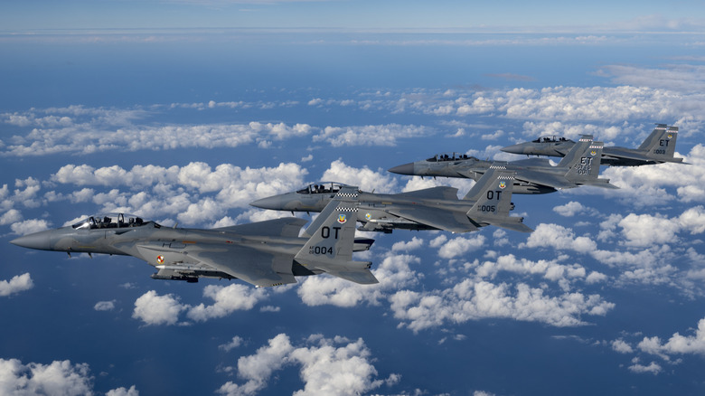 Group of four F-15 fighters from Eglin AFB flying in formation over ocean.