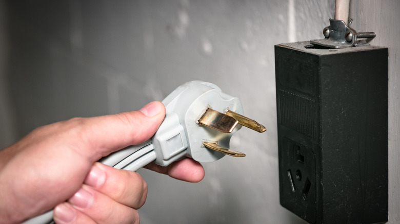 A picture of someone holding a 3 wire dryer plug next to a 3 wire 30 amp receptacle
