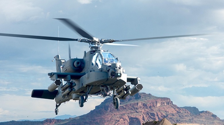 AH-64 Apache Attack Helicopter hovering over desert landscape