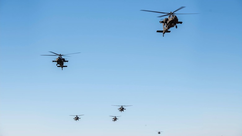 A group of Apache attack helicopters flying in loose formation