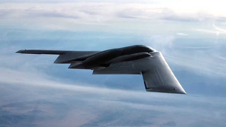 A B-2 Stealth Bomber flying over clouds on a test mission