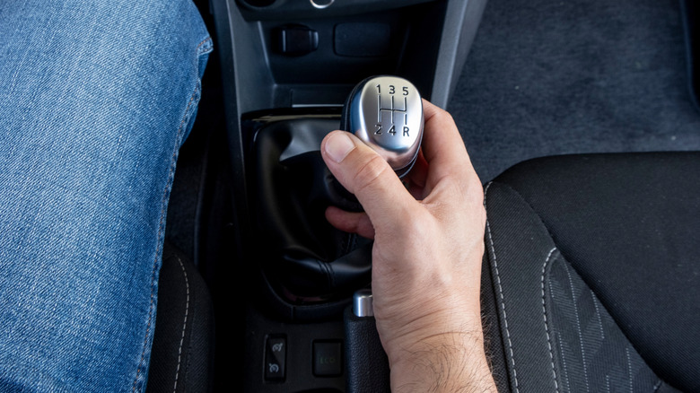 A driver changing gears with a manual transmission stick shift.