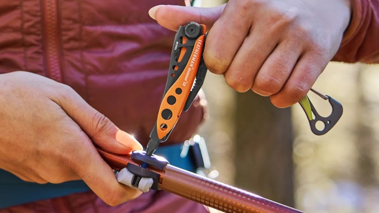A person using a Leatherman multitool on a pipe.
