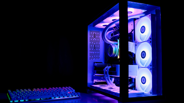 A PC with purple lighting next to a colorfully backlit keyboard