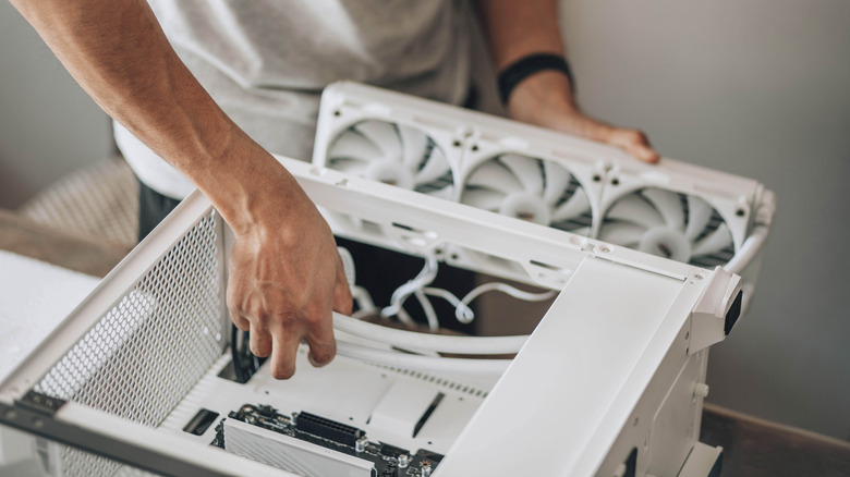 A person installing fans into a PC with a white case