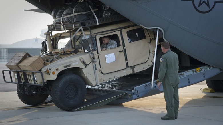 An Airman moves a Humvee off an aircraft as another watches