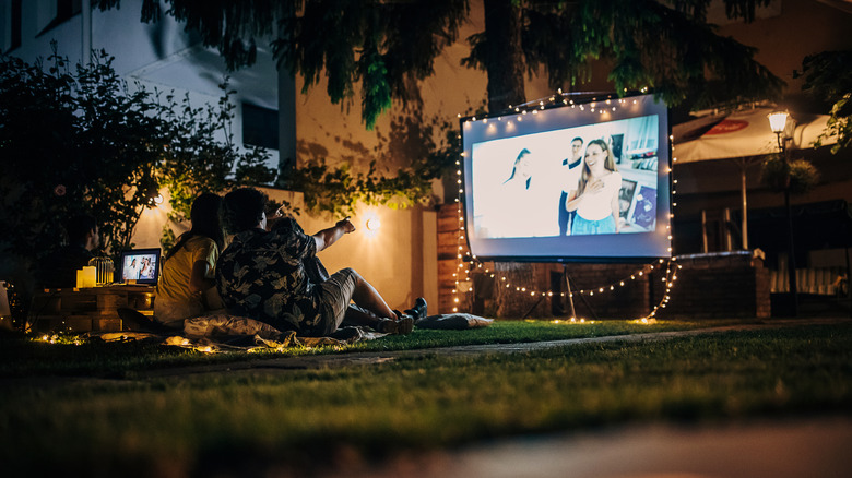 People using a projector setup outdoors in a residential backyard