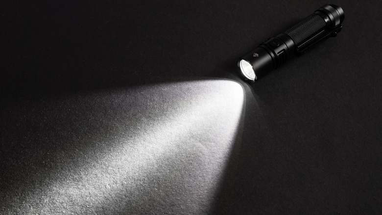 A flashlight producing a cone of light on the ground