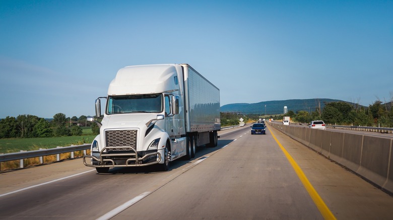 White tractor-trailer driving on highway