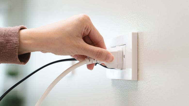 Closeup of a woman's hand plugging a cord into an outlet