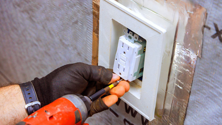 An electrician works on installing an electrical outlet in home
