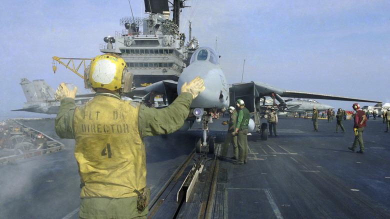 A Flight Director working on a busy aircraft carrier flight deck