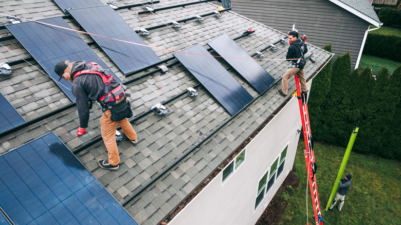 Workers installing solar panels on a roof