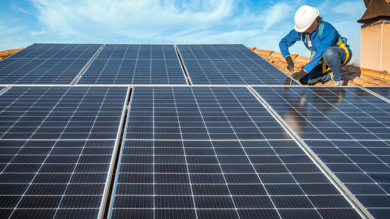 An engineer installing solar panels on a rooftop