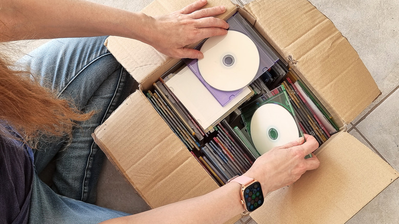Top-down view of a person opening a box full of CDs