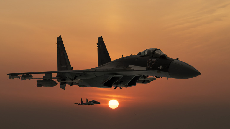 A pair of Su-35 fighter jets flying at sunset