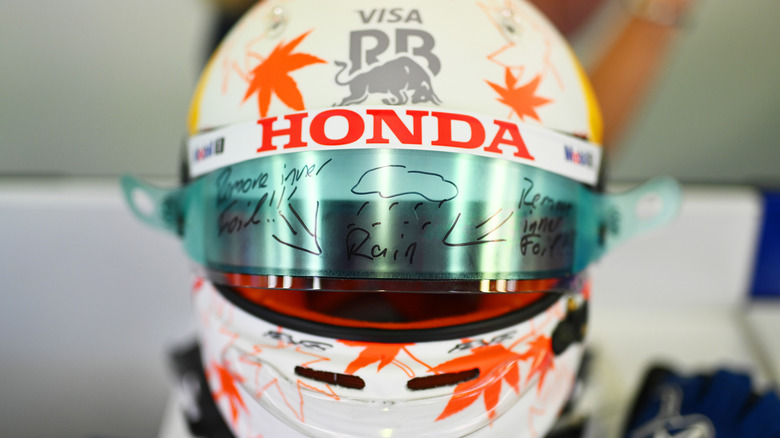 Yuki Tsunoda's racing helmet showing graphics written on visor tear-offs