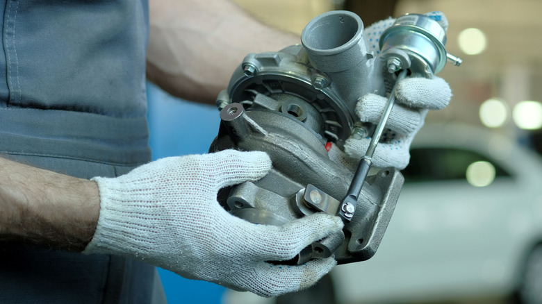 Mechanic with gloved hands holding a turbocharger