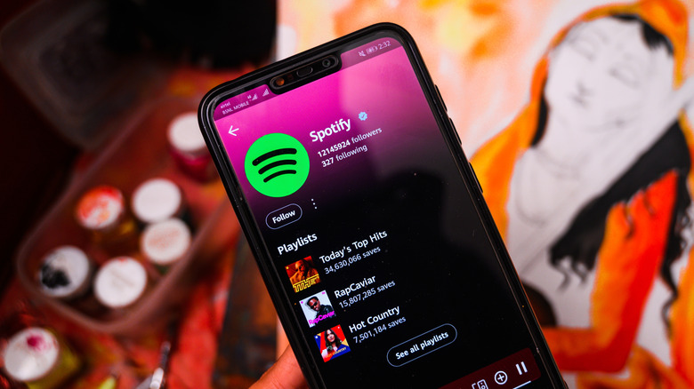 Phone showing Spotify playlist with painting in the background