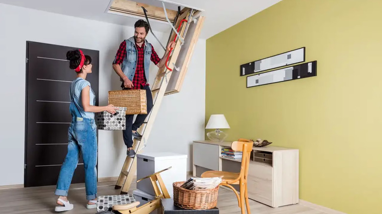 A man and a woman about to start storing items in an attic using a Fakro LWT Thermo attic ladder