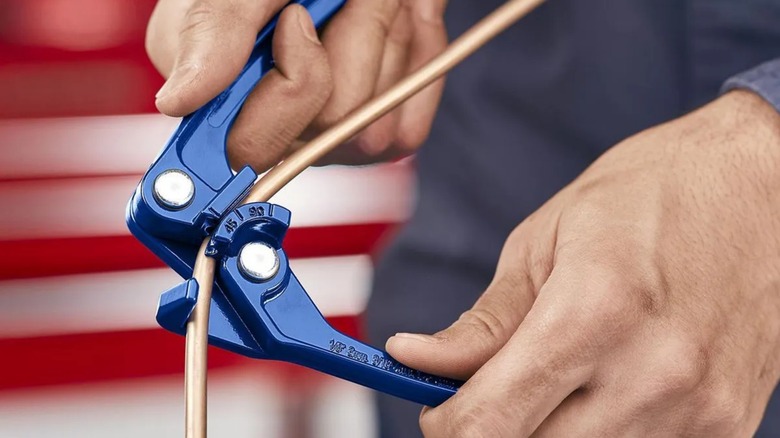 a person using a harbor freight pittsburgh tube bender to bend copper tubing