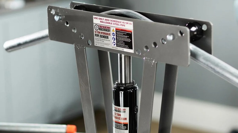 a harbor freight central machinery pipe bender being used to bend steel piping