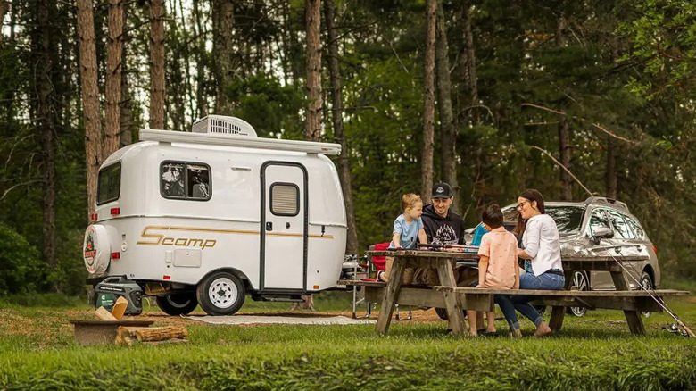 Family picnic in the woods with camper